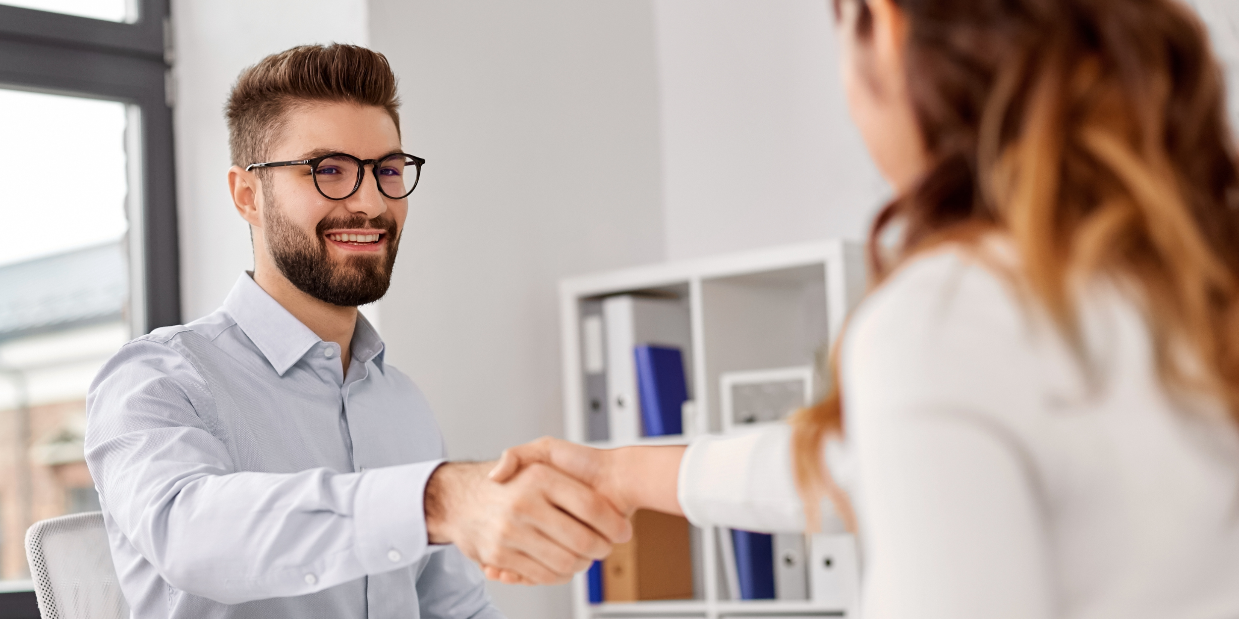 Handshake zwischen Führungskraft und Teammitglied als Symbol für ein verlässliches Mitarbeitergespräch zur Steuerung von Zielen, Leistung und Entwicklung.